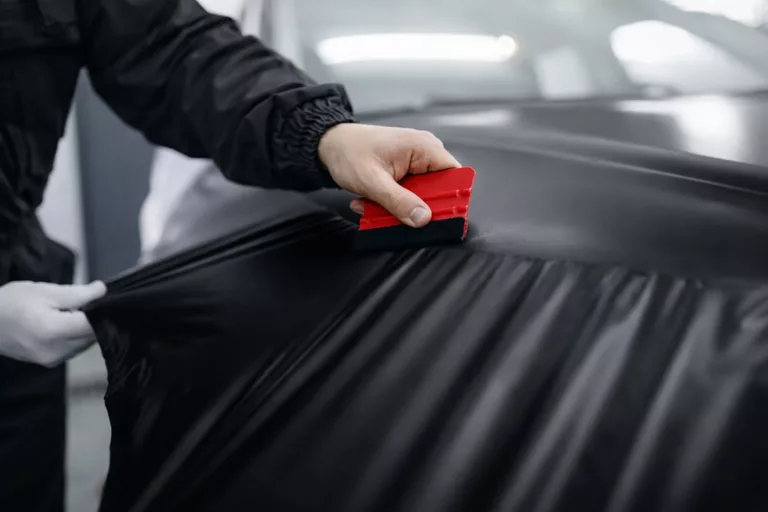 Stagiaire appliquant un covering automobile pendant une formation professionnelle
